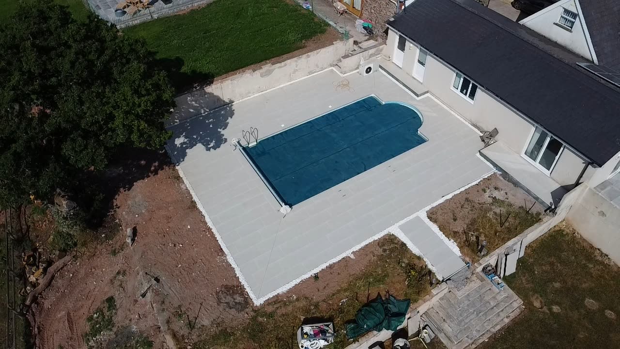Aerial view of a garden swimming pool with cover, surrounded by newly laid paving