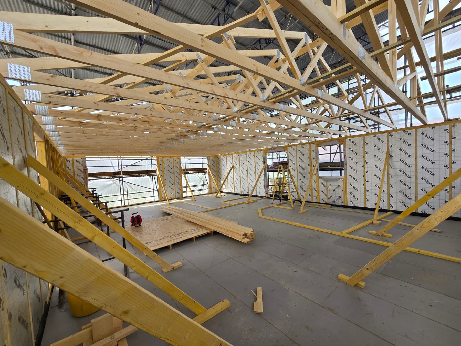 Roof trusses above insulated timber-framed walls inside a bespoke home under construction