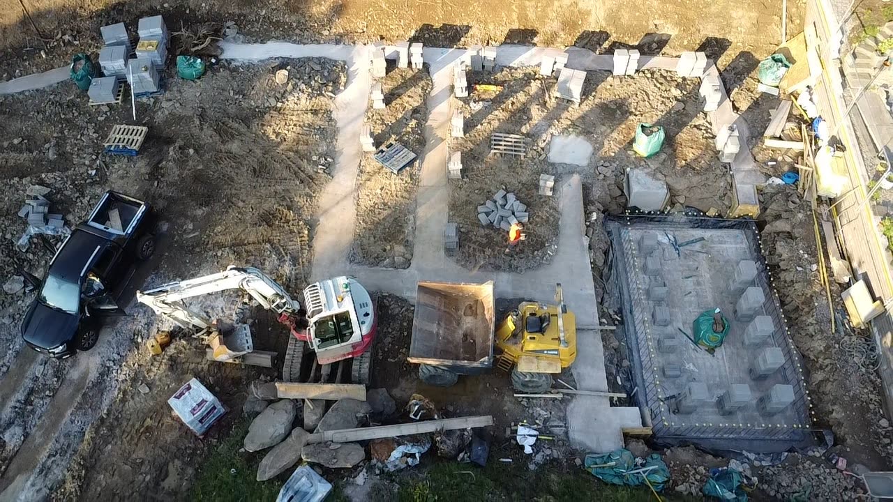 Aerial view of a construction site with several building foundations, blockwork and machinery