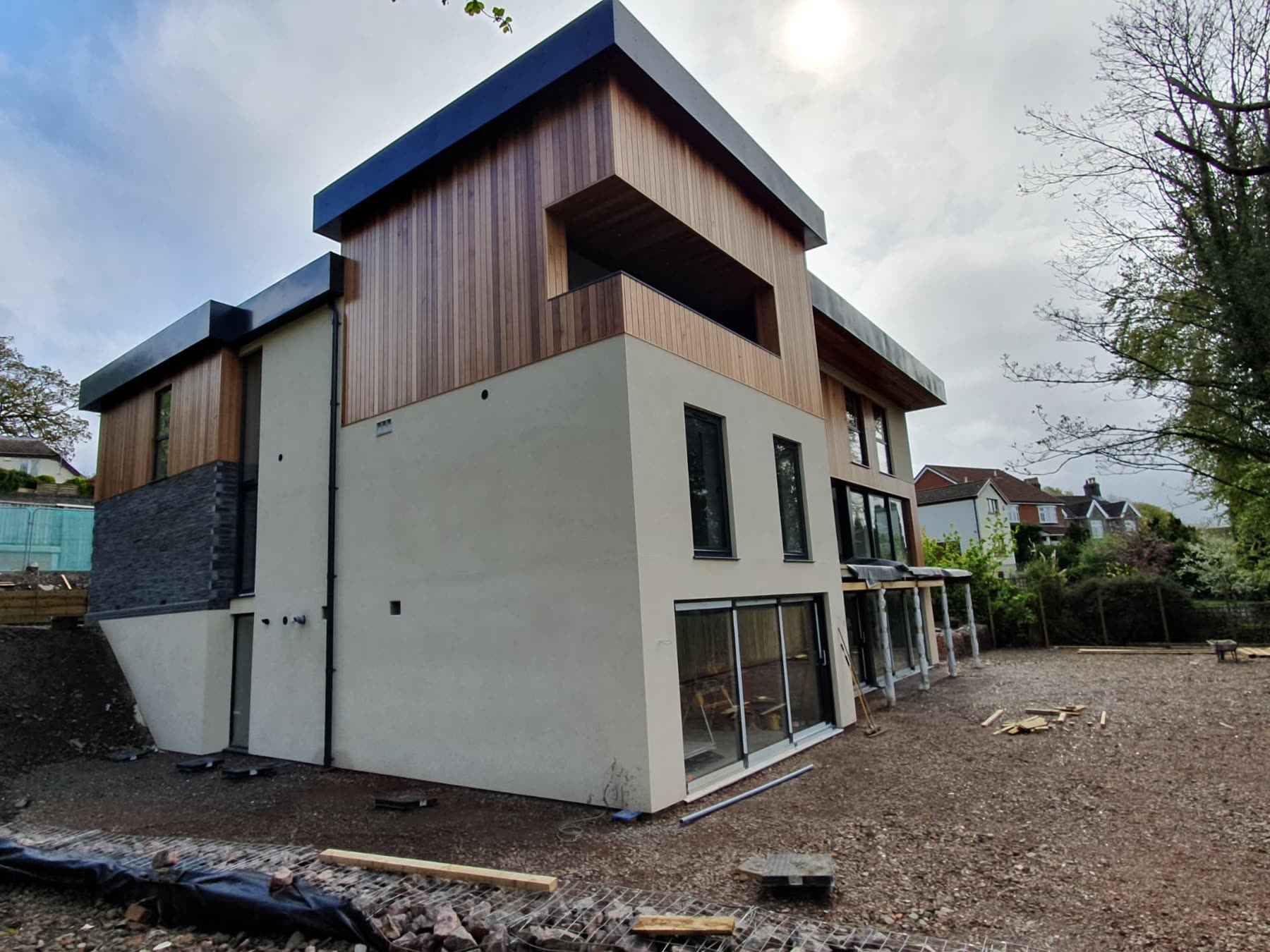 Contemporary house with cedar cladding, render and large glazed windows close to completion