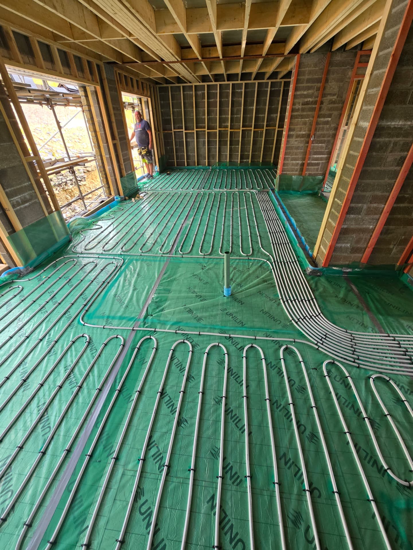 Underfloor heating pipework being laid across insulation boards in a new build